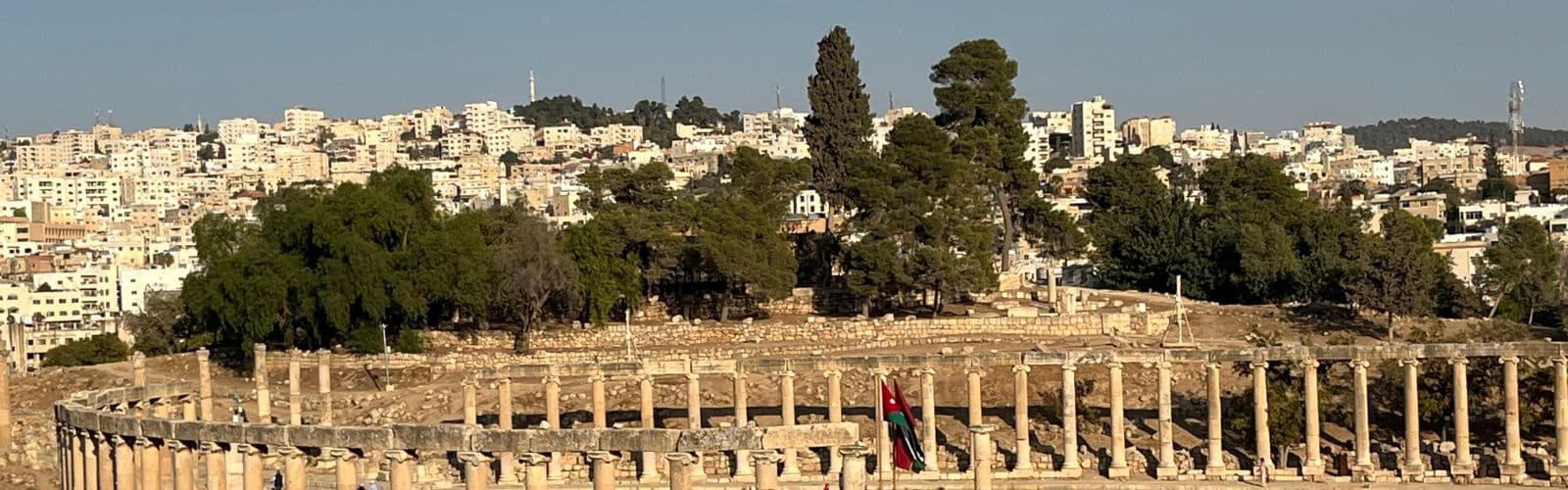 Pillars forming the shape of an oval stand in front of the city of Amman. 